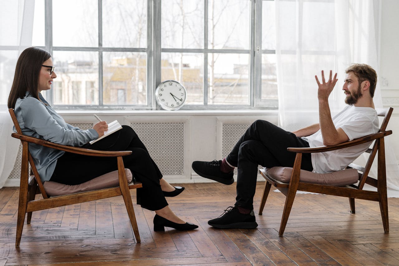 Person In Black Pants And Black Shoes Sitting On Brown Wooden Chair 4101143